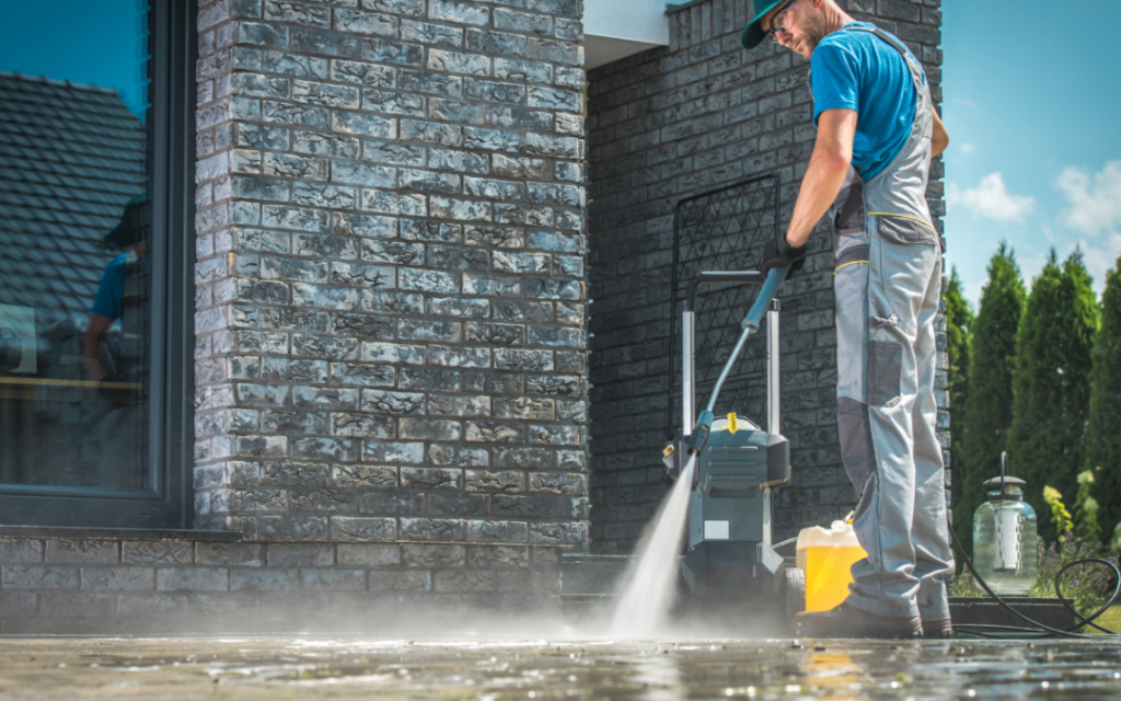 Man pressure washing the front sidewalk of a business.