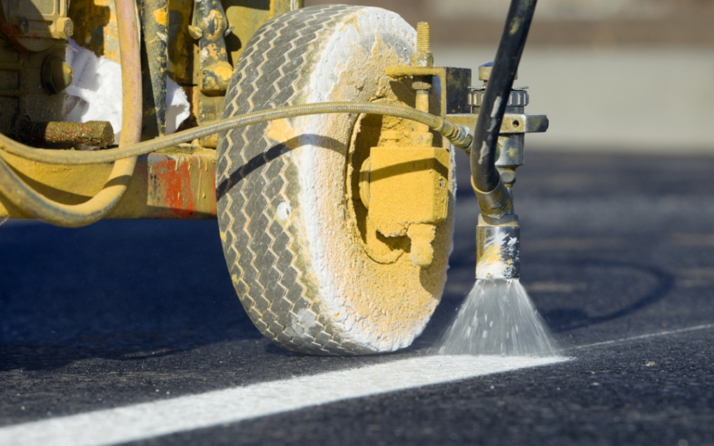 machine painting white lines on a parking lot