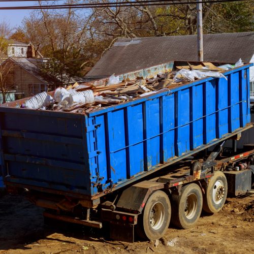Roll off dumpster full of debris being loaded onto a truck.